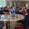 People sat around tables watching a presenter