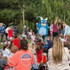 Families gathered together in a park in front of a person dressed as the character Bluey