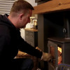 Man closing the door of his log-burner in his living room