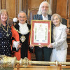 Photo of the Mayor, Mayoress and Charlie and Mrs Lansborough in the Council Chamber holding the scroll