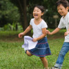 two children running and laughing in a park