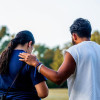Man placing a hand on a woman's shoulder in a comforting way