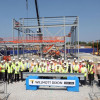 A group of contractors, councillors, teachers and students stand outside the new steel frame of the new Mosslands School