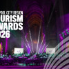 Liverpool City Region Tourism Awards 2026 event inside a large cathedral-like venue, illuminated with purple and teal stage lighting. Banquet tables fill the hall beneath dramatic spotlights, with the Tourism Awards 2026 branding displayed prominently on the left and a graphic motif in the lower right corner.
