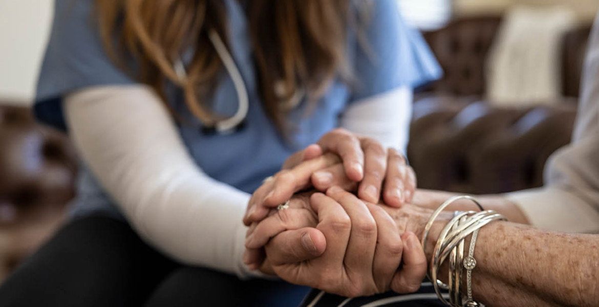 Close up image of a younger and older person holding hands