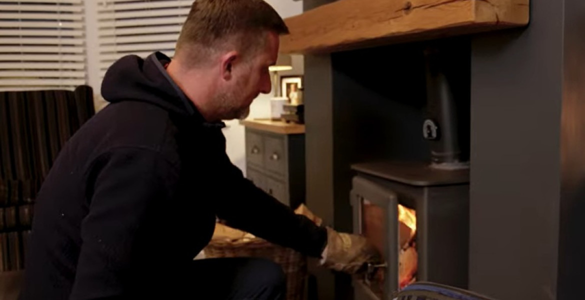 Man closing the door of his log-burner in his living room