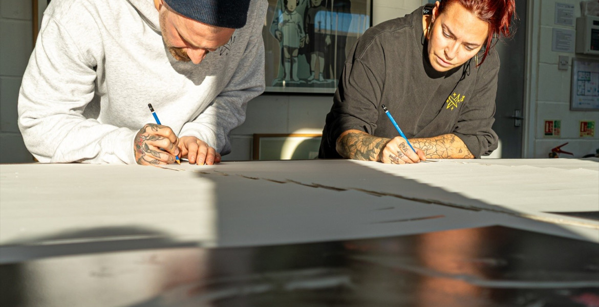 Artists SNIK drawing mural leaning on table