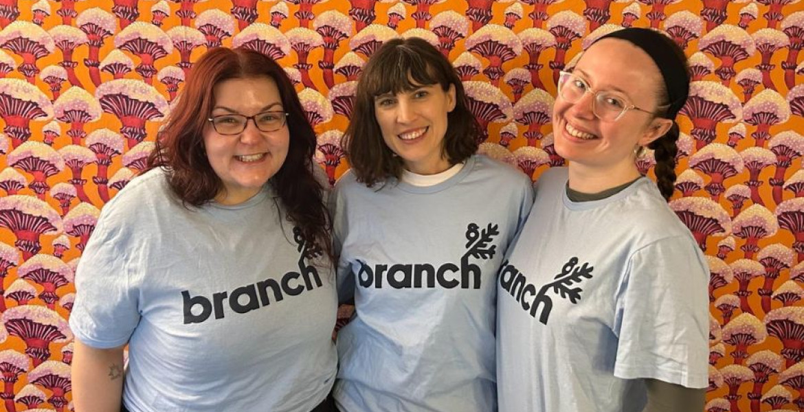 Three women stand posing and smiling for a group photo