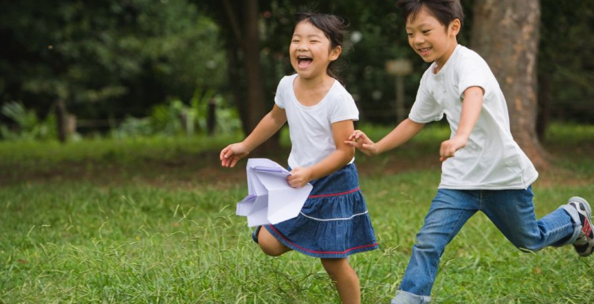 two children running and laughing in a park