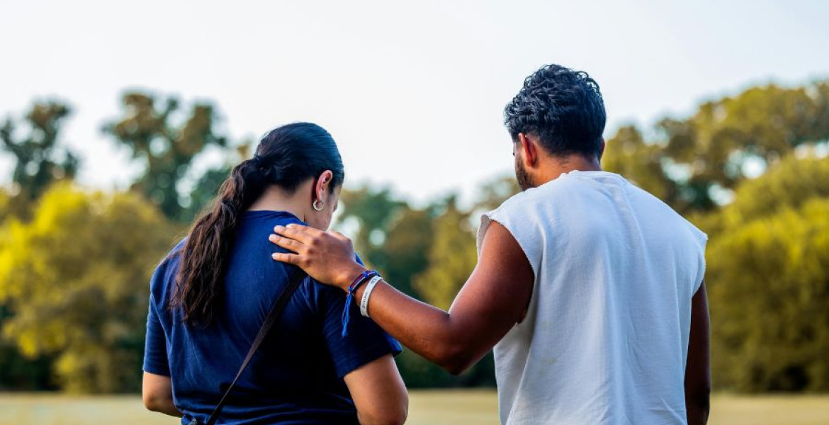 Man placing a hand on a woman's shoulder in a comforting way