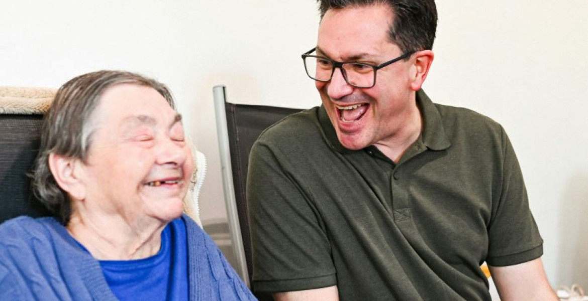 2 men smiling, one is elderly and the other is younger
