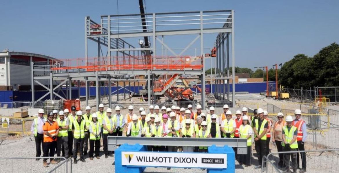 A group of contractors, councillors, teachers and students stand outside the new steel frame of the new Mosslands School