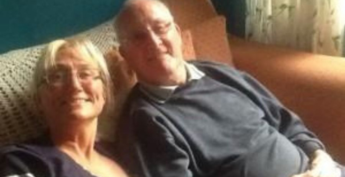 Man and woman sitting on the couch smiling at the camera