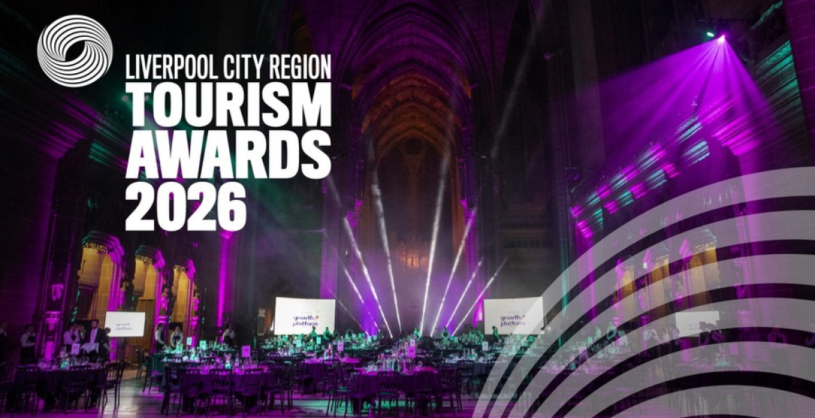 Liverpool City Region Tourism Awards 2026 event inside a large cathedral-like venue, illuminated with purple and teal stage lighting. Banquet tables fill the hall beneath dramatic spotlights, with the Tourism Awards 2026 branding displayed prominently on the left and a graphic motif in the lower right corner.